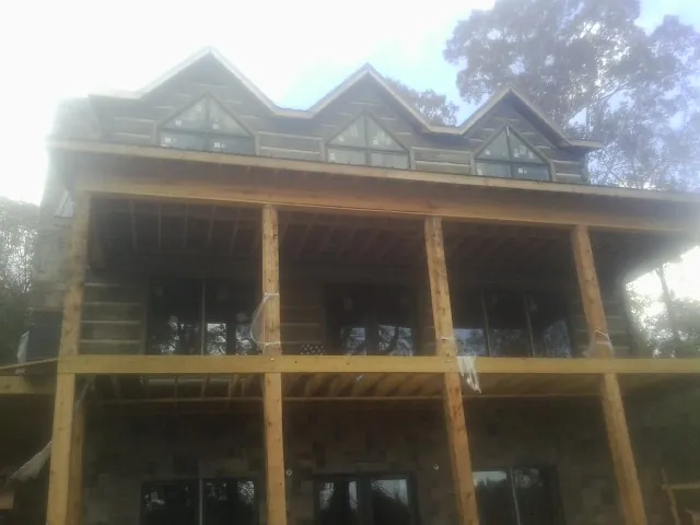 Dormers and porch framing on a large log home under construction — Roof Coating work by our crew in Williamsfield