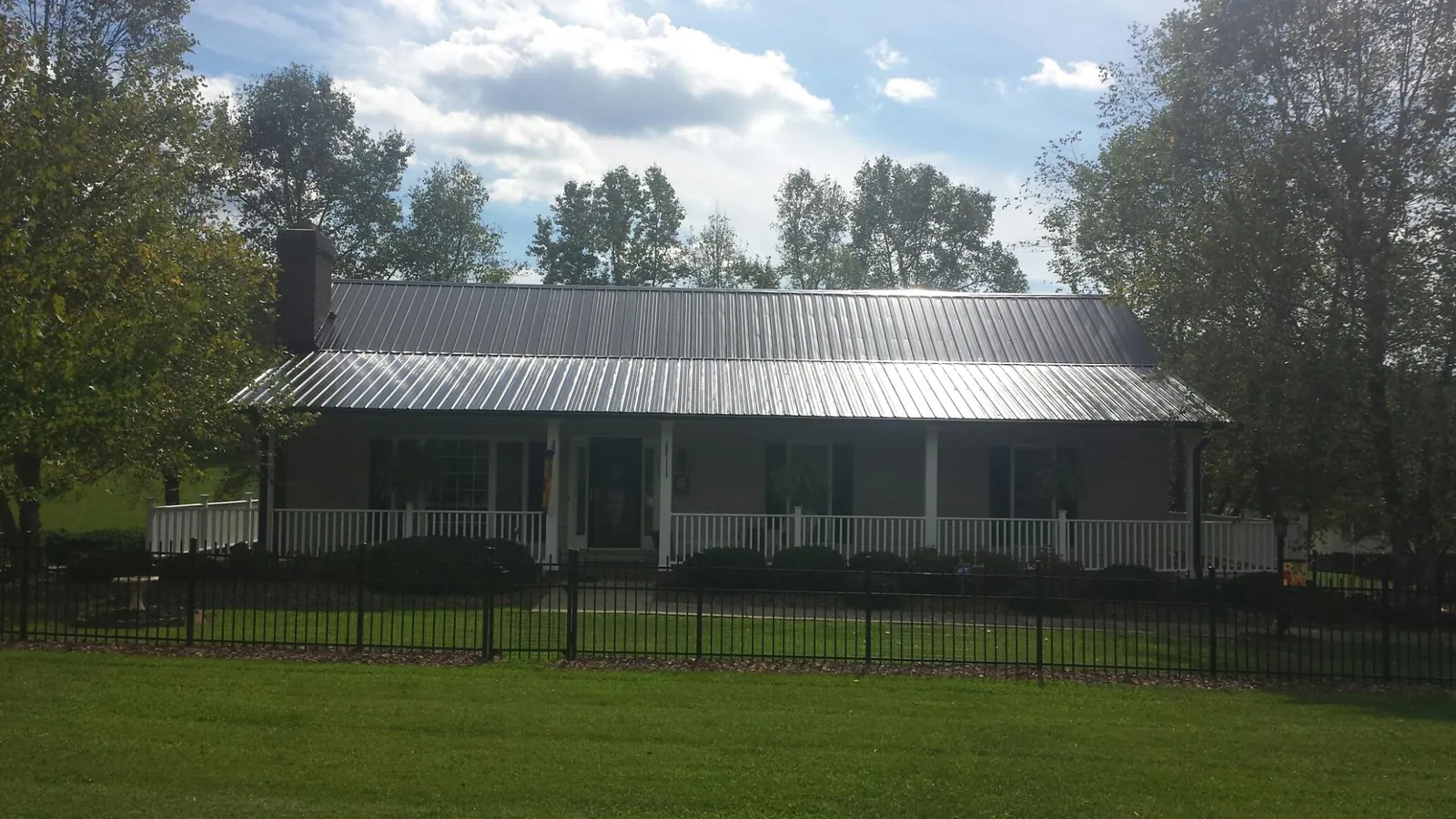Gray metal roof on a brick ranch with a full width front porch — Gutter Guard Installation work by our crew in Williamsfield