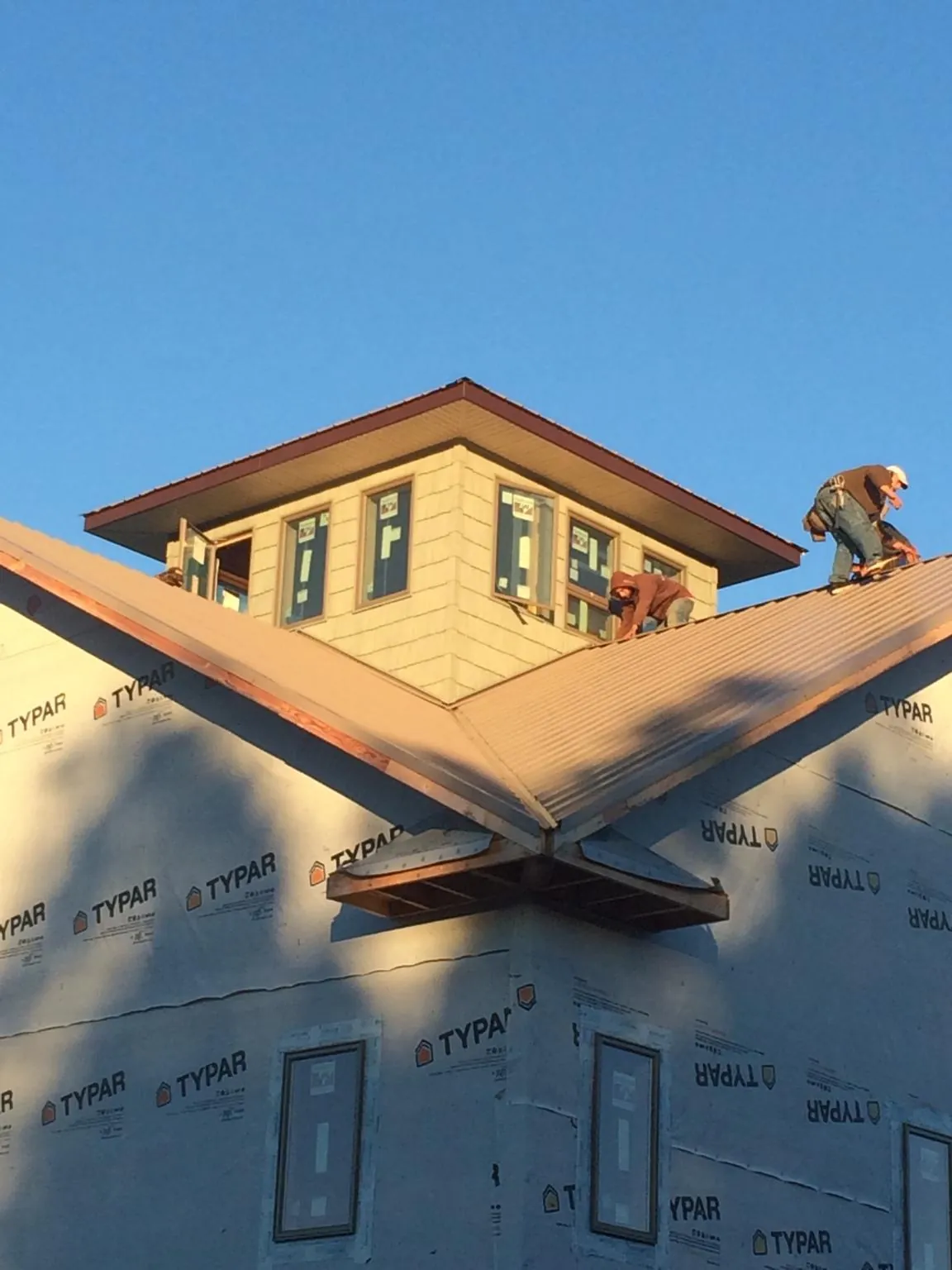 Roofers working around a rooftop cupola on a new metal roof at sunset — Roof Waterproofing in Williamsfield by Roofing Brothers